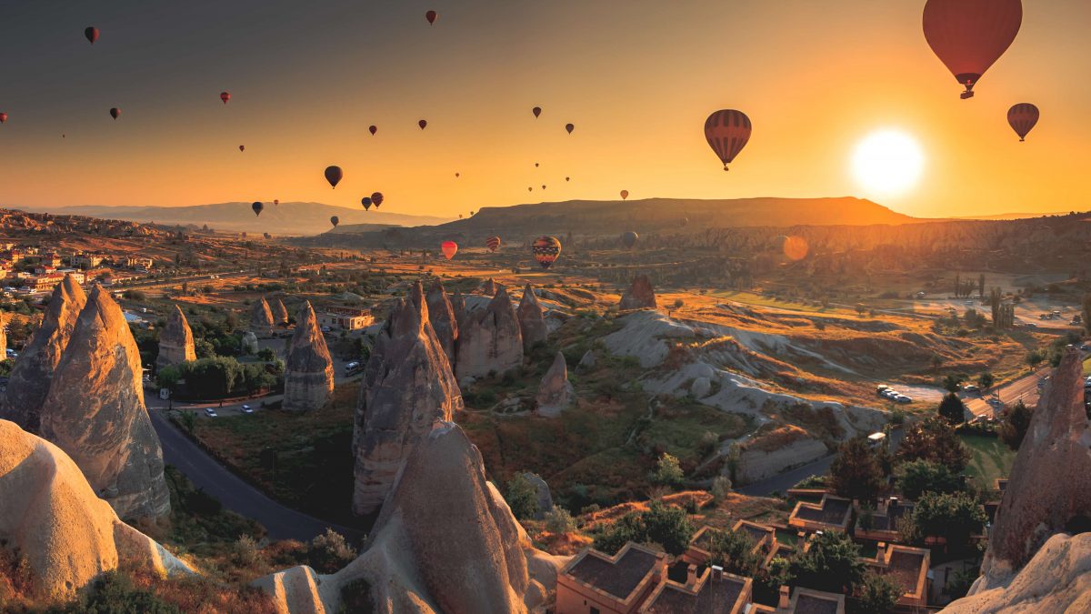 Luchtballonnen zweven boven de aardpiramides van Cappadocië