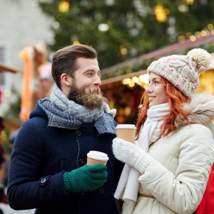 Man en vrouw met warm drinken op een kerstmarkt