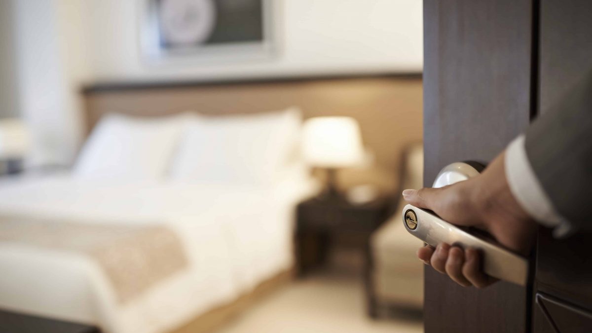 Een hotelmedewerker opent de deur van een hotelkamer