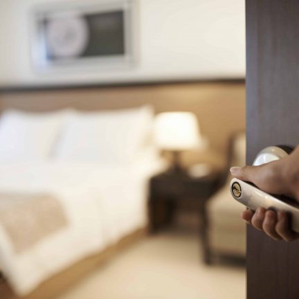 Een hotelmedewerker opent de deur van een hotelkamer