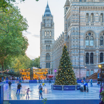 Ijsbaan en kerstmarkt voor het natural history museum in londen met uitzicht op de big ben