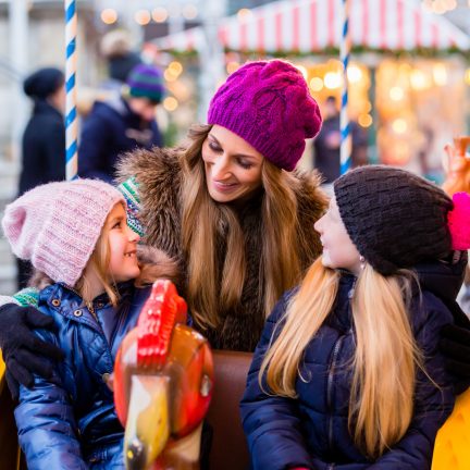 Vrouw met kinderen in een draaimolen op de kerstmarkt