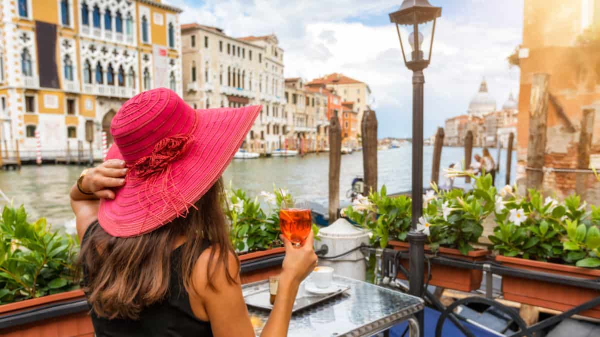 Vrouw geniet op een terras van een drankje met uitzicht op de Canale Grande in Venetië, Italië
