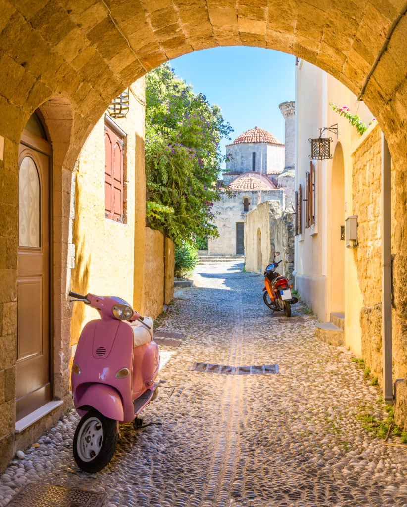 Een smal straatje met een scooter op Rhodos in Griekenland