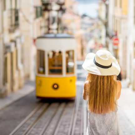 vrouw met hoed kijkt naar bekende gele tram lissabon portugal