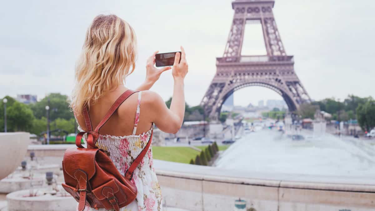 Vrouwelijke toerist met rugzak neemt een foto van de Eiffeltoren in Parijs, Frankrijk