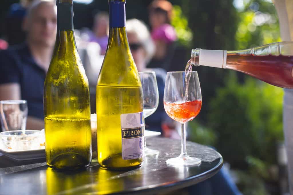 Glas wijn wordt ingeschonken met meerdere glazen wijn op tafel